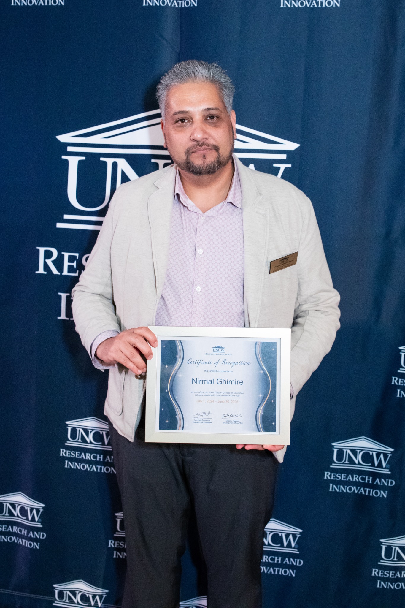 Nirmal Ghimire holding his UNCW research recognition certificate